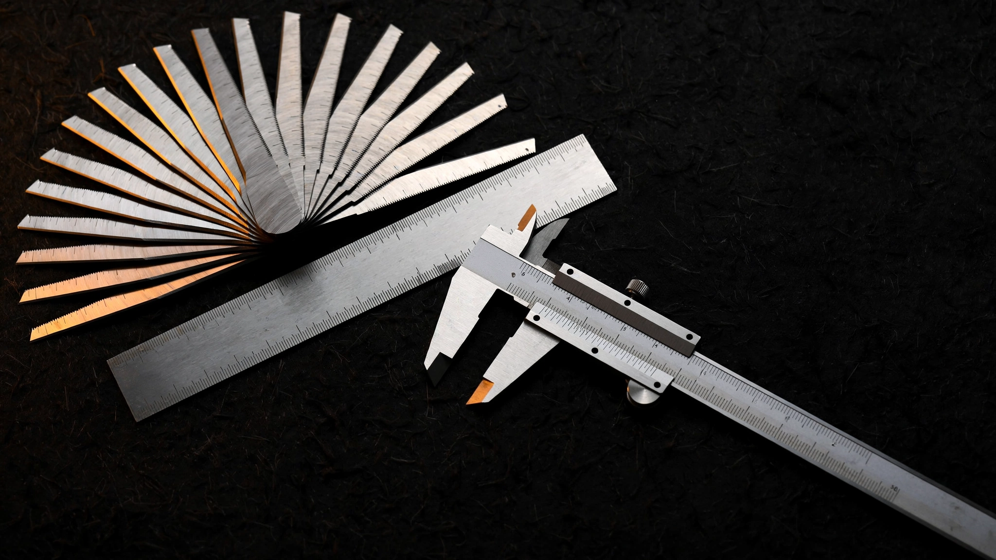 Precision machinist gauges fanned open on dark felt under raking light.