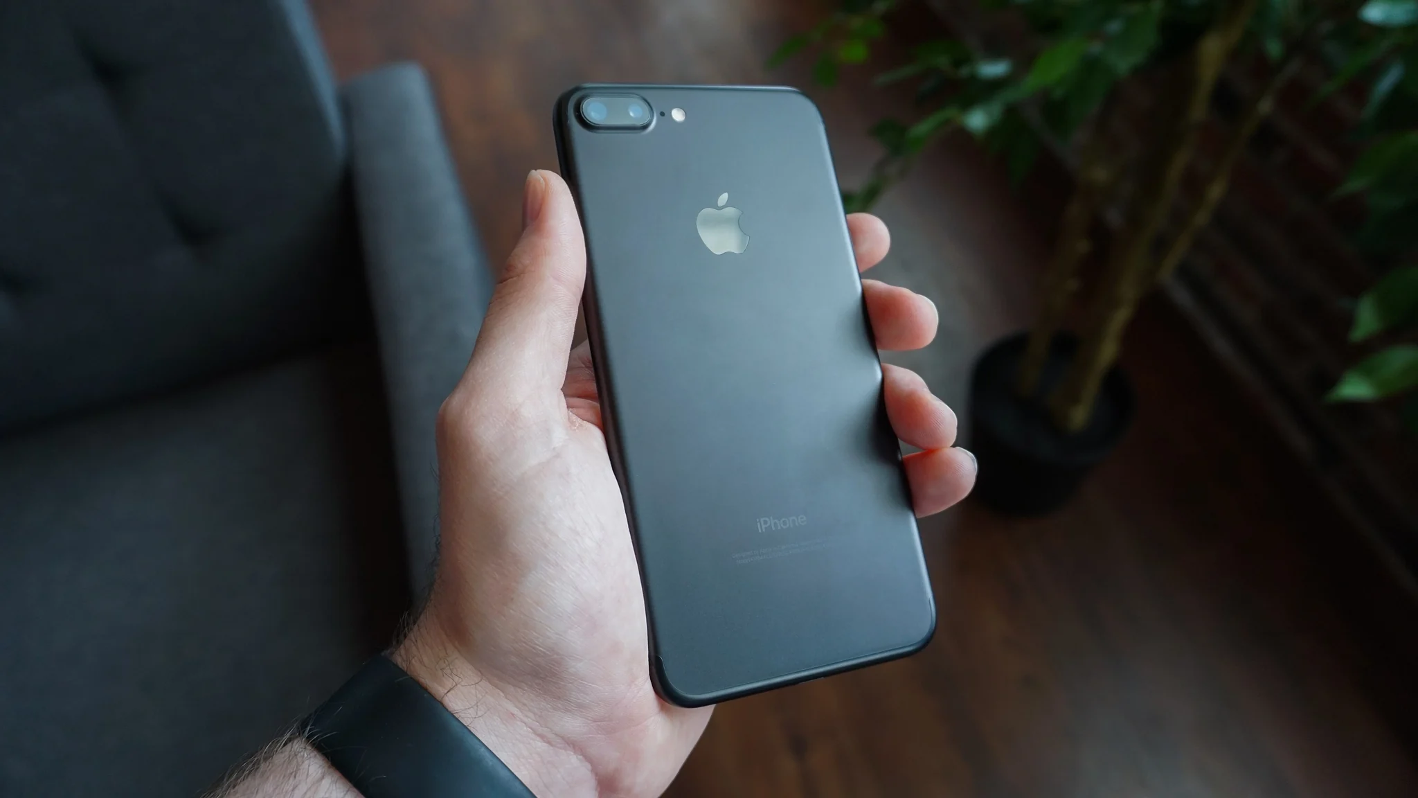 Black smartphone held in one hand, screen off.