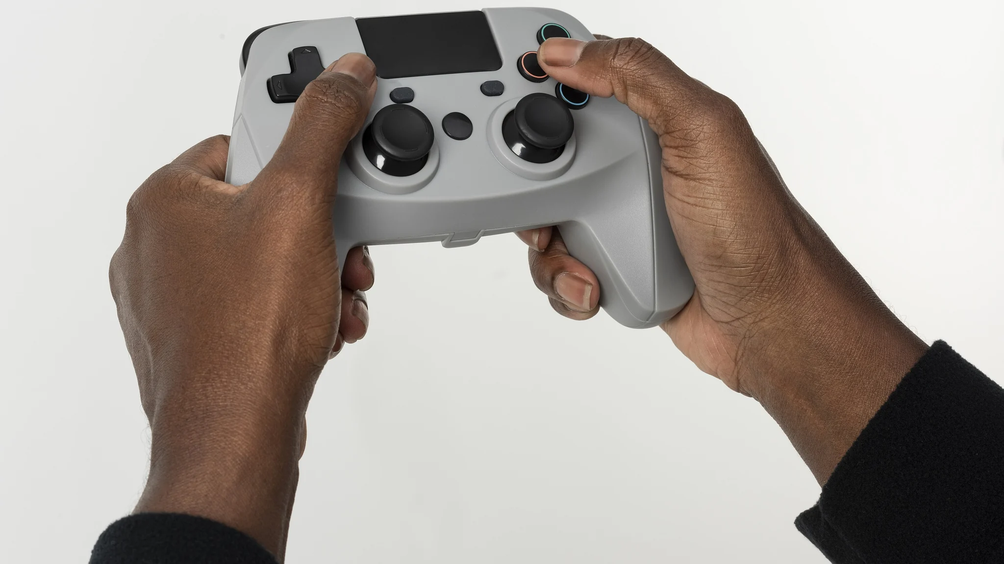 Hands holding a video game controller in front of a screen.